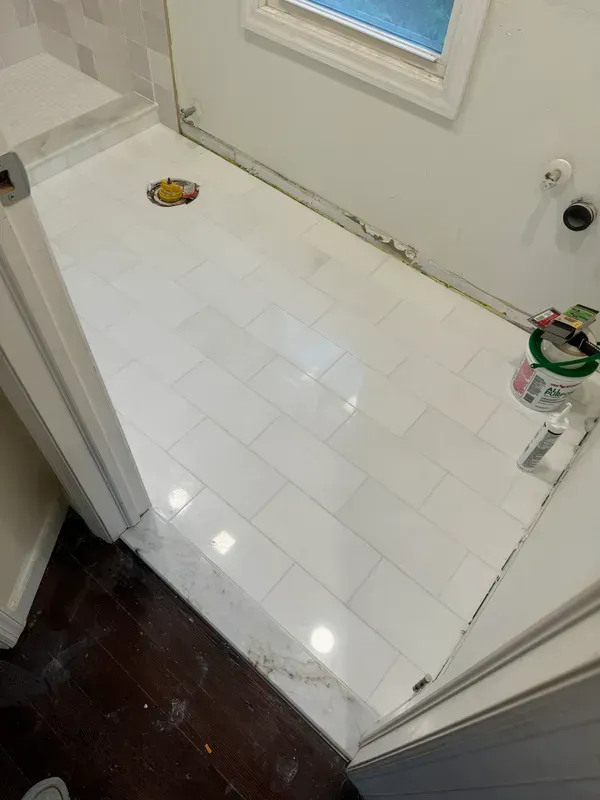 A bathroom with white tile floors and a window.