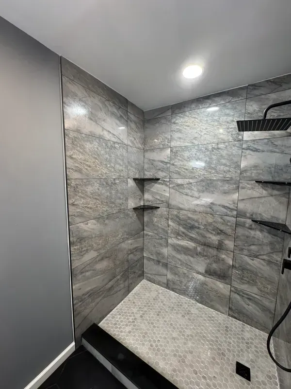 A bathroom with a walk in shower and a shower head.