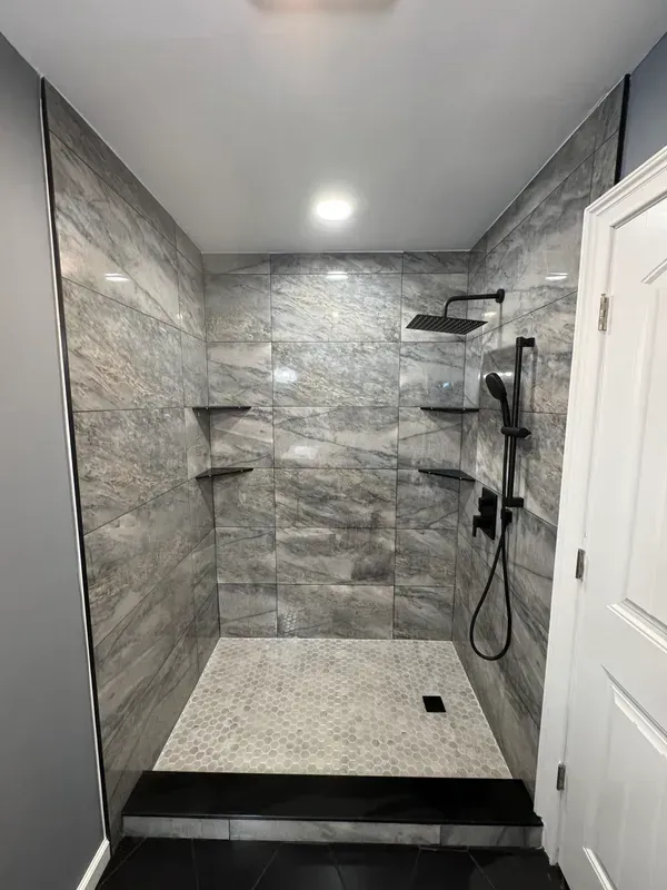 A bathroom with a walk in shower and a shower head.