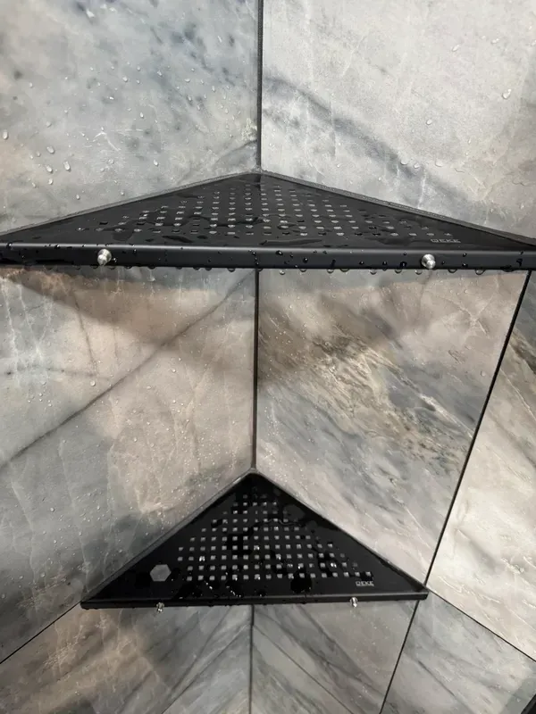 Two black corner shelves are sitting on a tiled wall.
