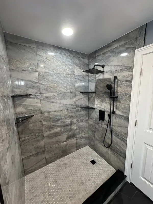 A bathroom with a walk in shower and a black shower head.