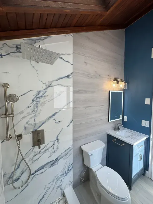 A bathroom with a toilet , sink , shower and mirror.