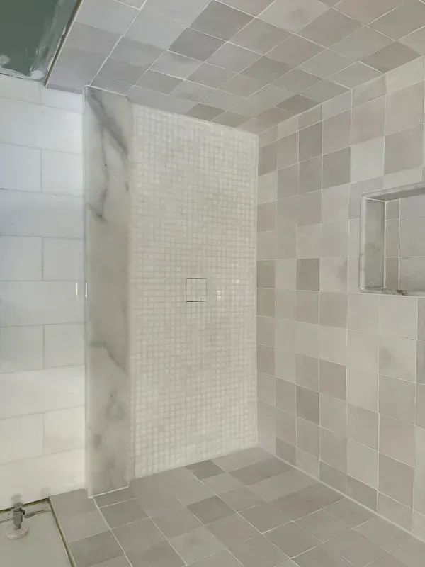 A bathroom with white tiles and a walk in shower.