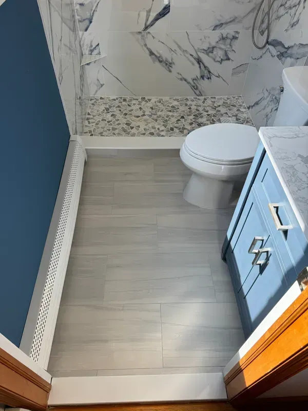 A bathroom with a toilet , sink and shower.