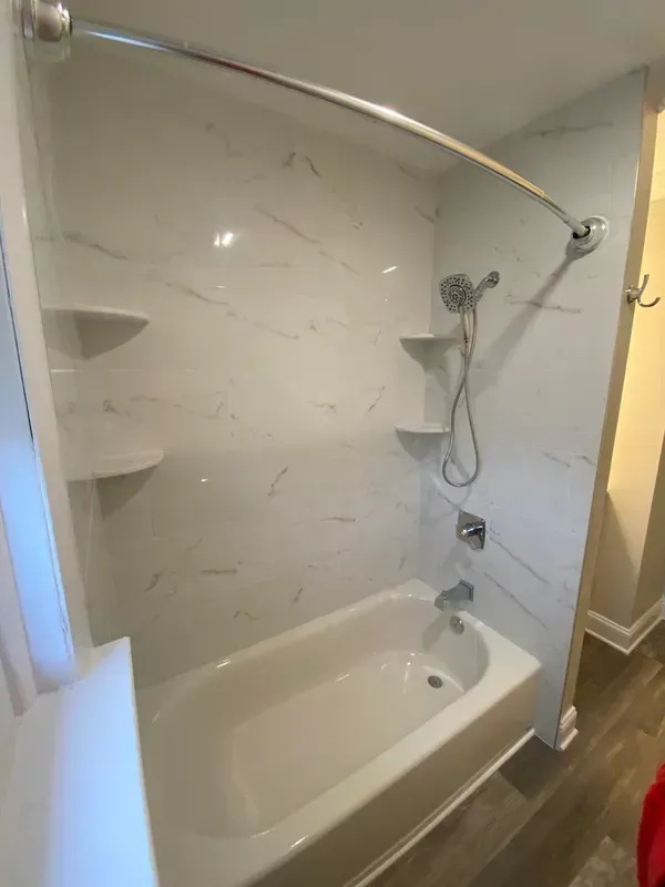 A bathtub with a shower head and shelves in a bathroom.