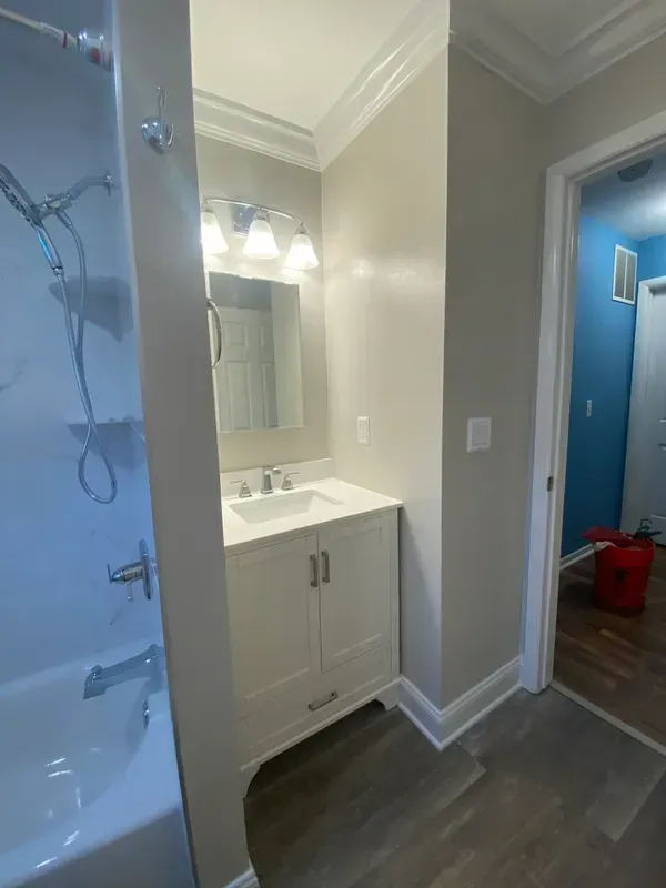 A bathroom with a sink , tub , shower and mirror.