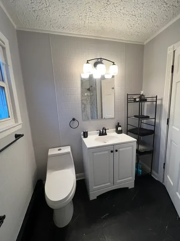 A bathroom with a toilet , sink and mirror.