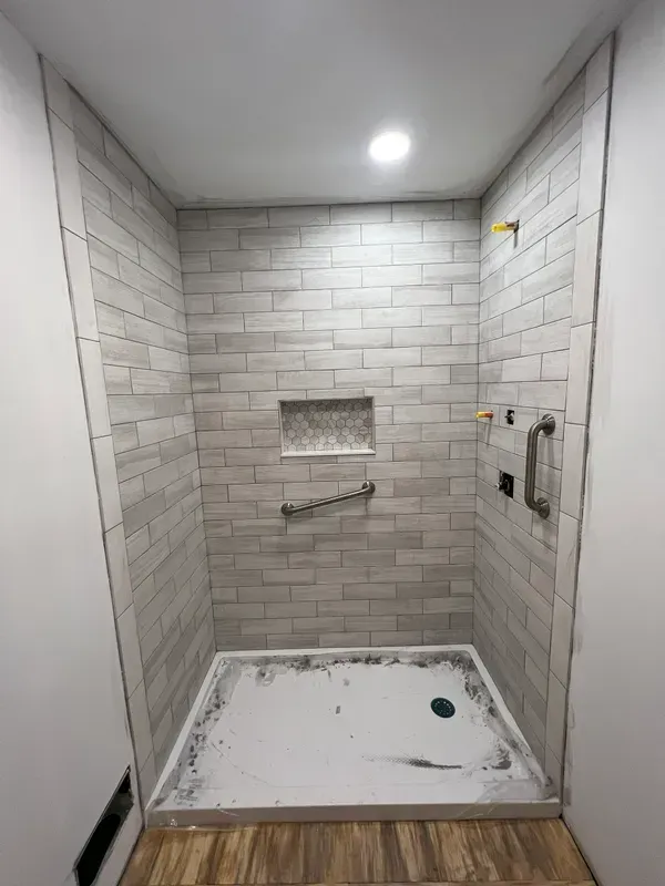 A bathroom with a walk in shower and a brick wall.