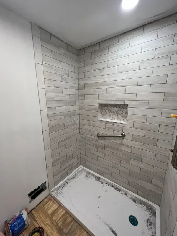 A bathroom with a walk in shower and a brick wall.