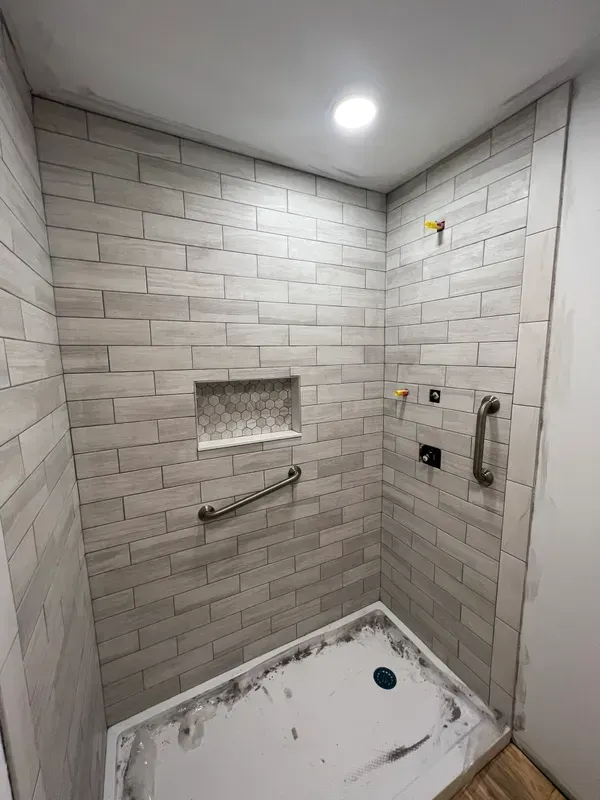 A bathroom with a walk in shower and a brick wall.