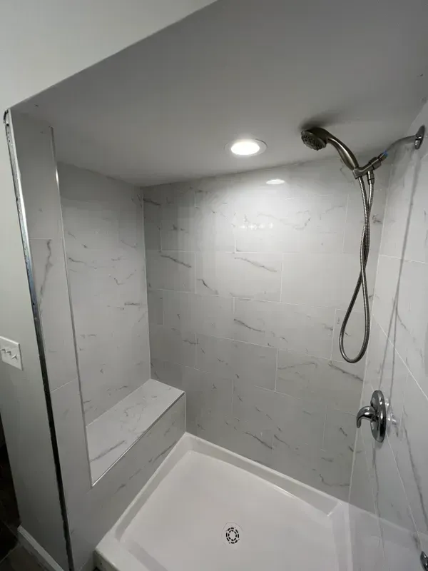 A bathroom with a walk in shower and a shower head.