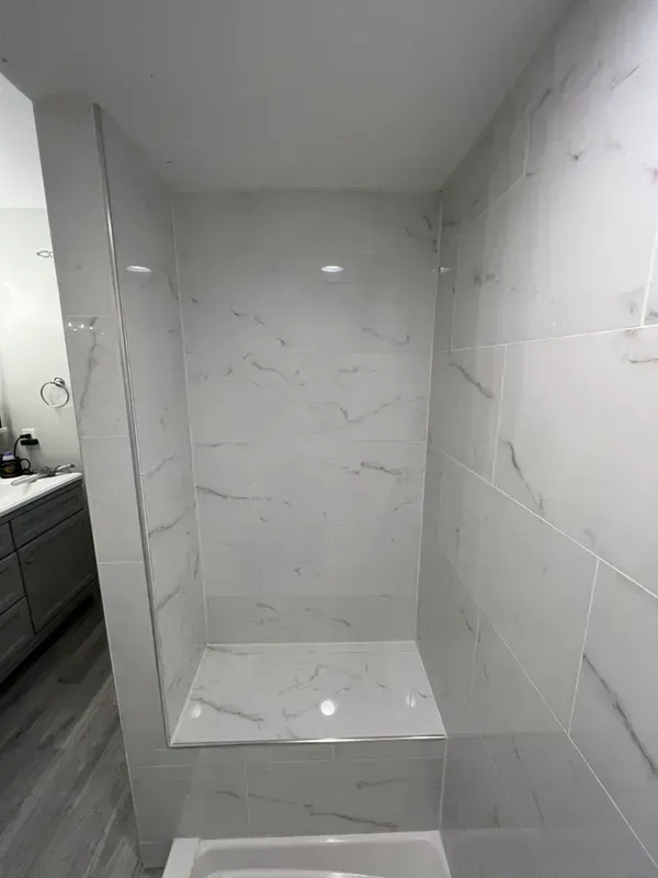 A bathroom with a walk in shower and a sink.