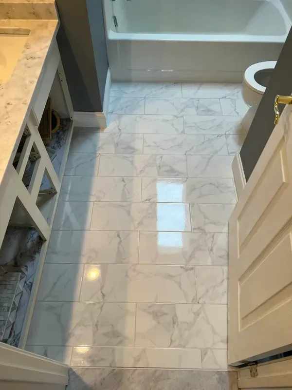 A bathroom with a marble floor , sink , toilet and bathtub.