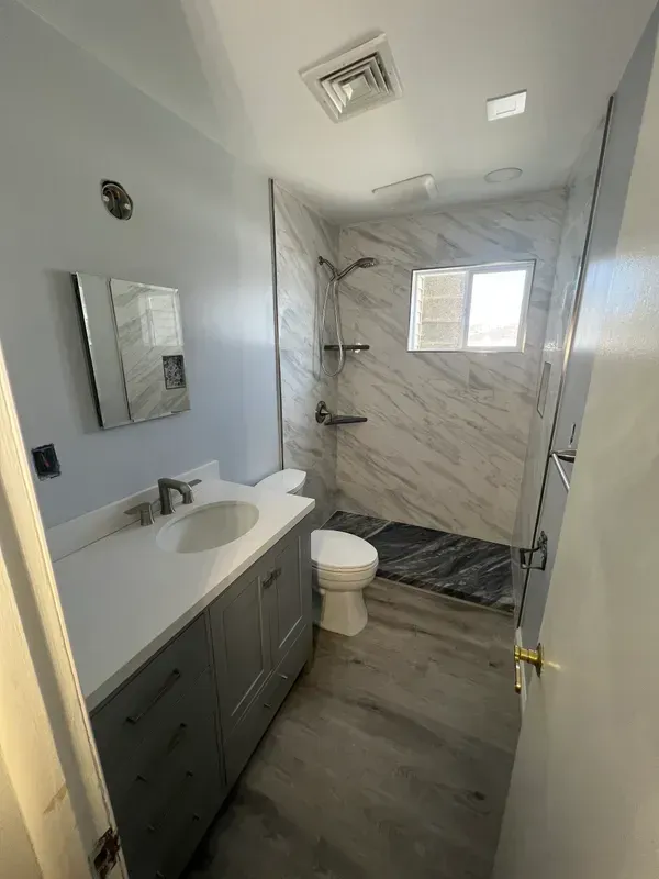 A bathroom with a toilet , sink and shower.