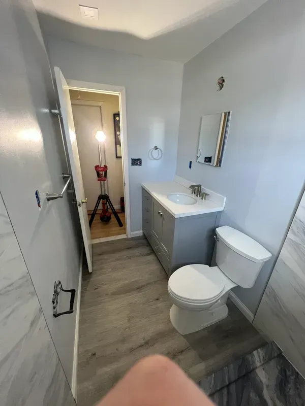 A bathroom with a toilet , sink and mirror.