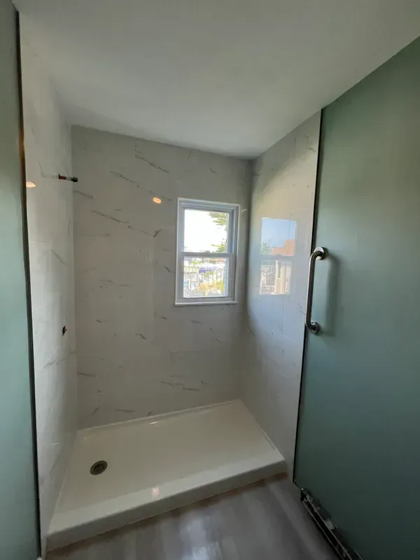 A bathroom with a walk in shower and a window.