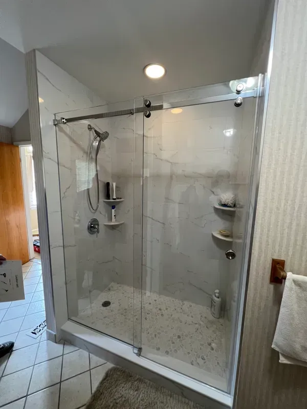 A bathroom with a sliding glass shower door and a shower head.