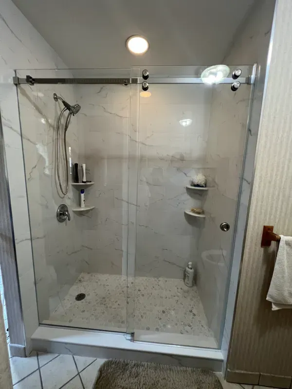 A bathroom with a sliding glass shower door and a shower head.