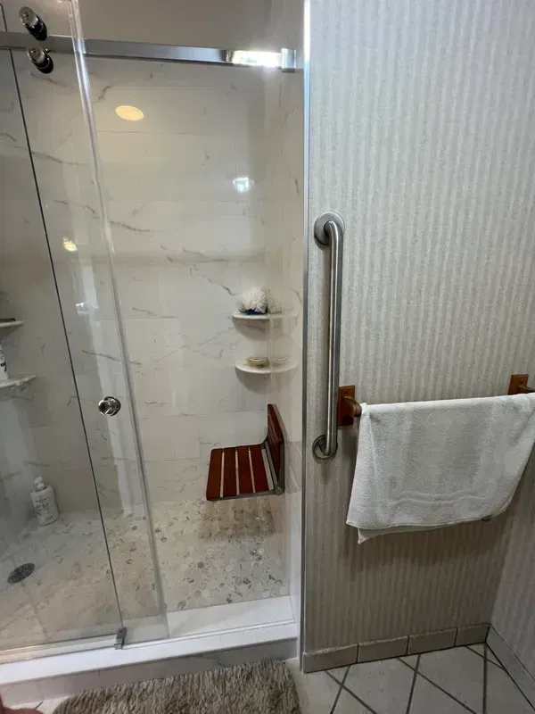 A bathroom with a sliding glass shower door and a towel rack.