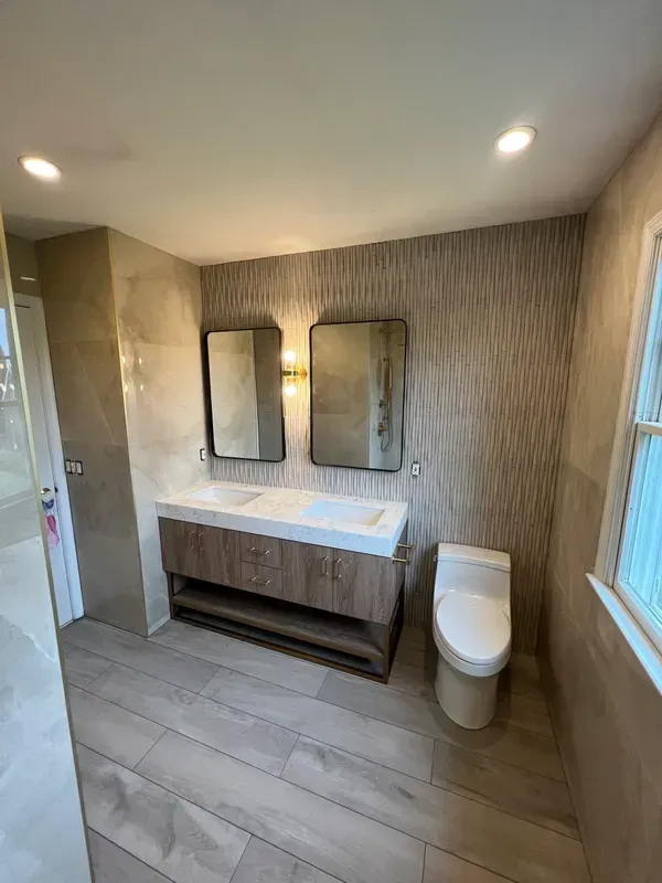 A bathroom with a toilet , sink and mirrors.