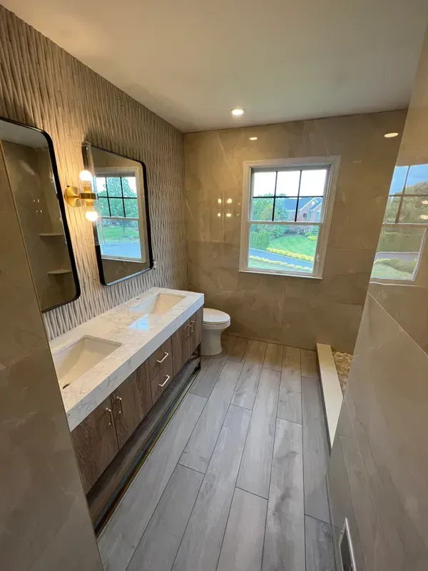 A bathroom with two sinks , a toilet , and a window.