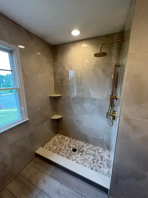 A bathroom with a walk in shower and a window.