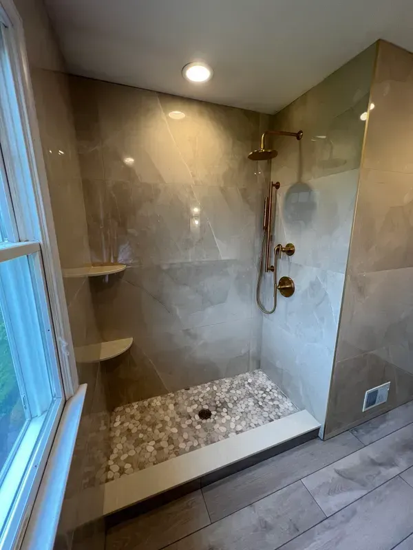A bathroom with a walk in shower and a window.