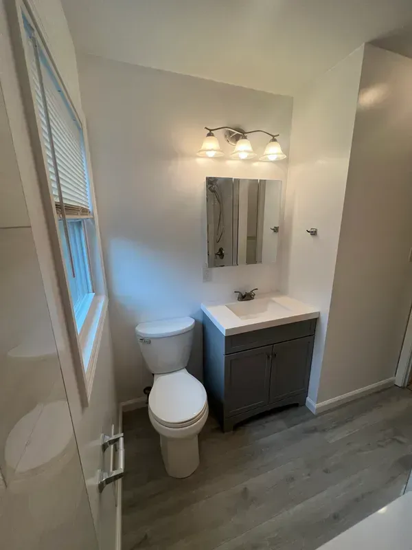 A bathroom with a toilet , sink and mirror.