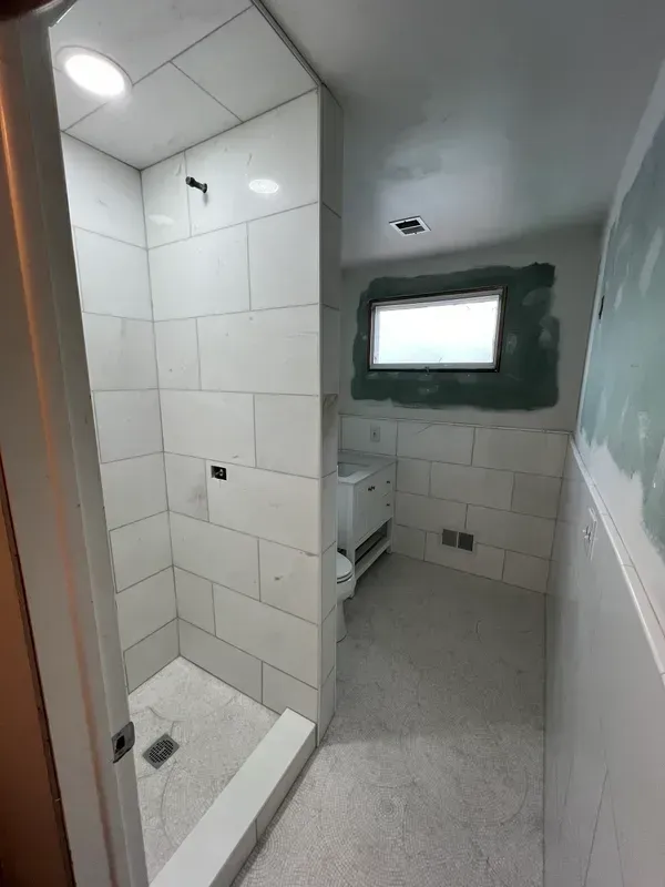 A bathroom with a walk in shower and a window.