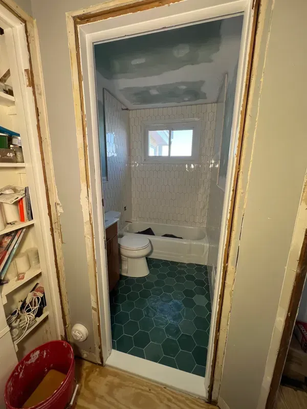 A bathroom with a toilet , tub , and window.
