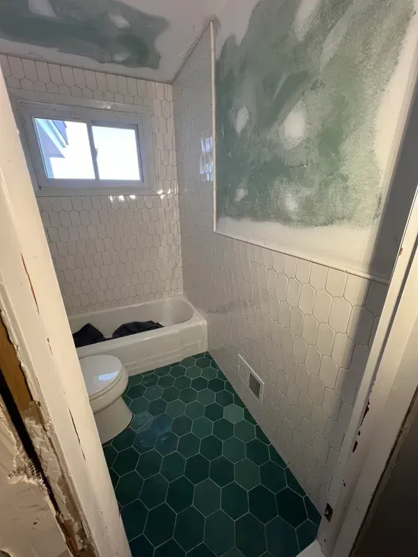 A bathroom with a toilet , tub and window