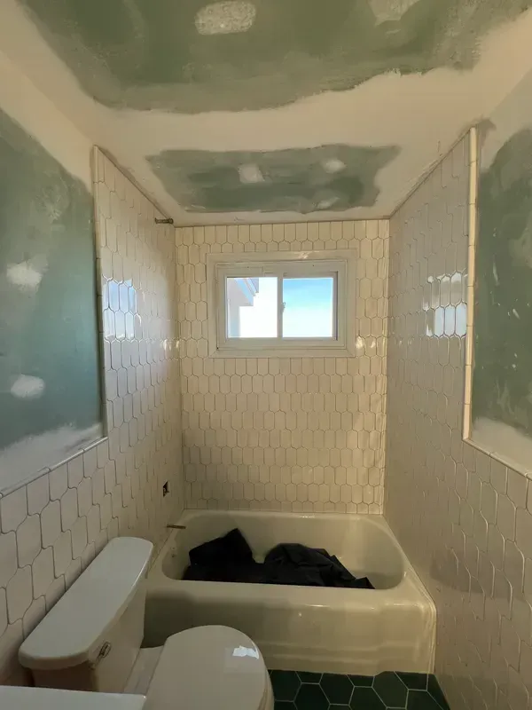 A bathroom with a toilet , tub , and window.