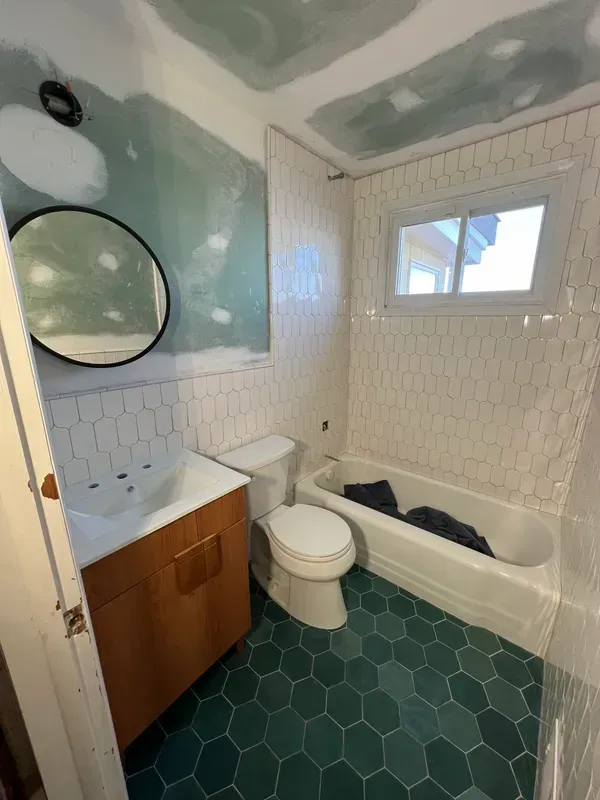 A bathroom with a toilet , sink , tub and mirror.