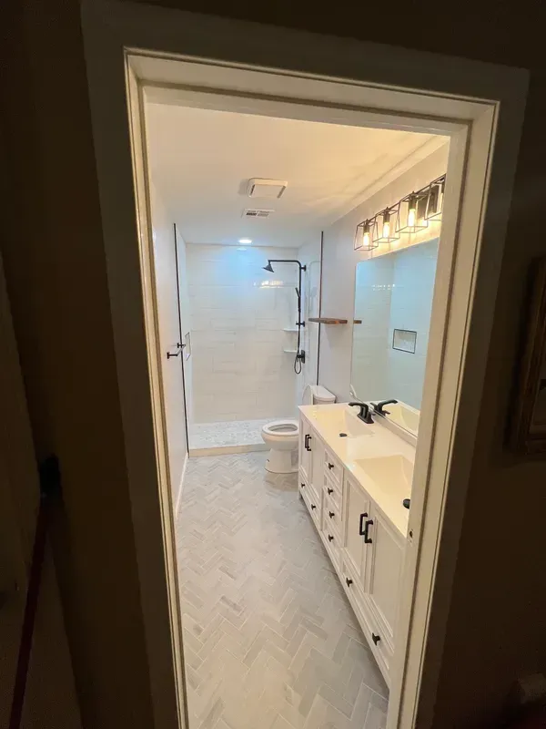 A bathroom with a toilet , sink , shower and mirror.