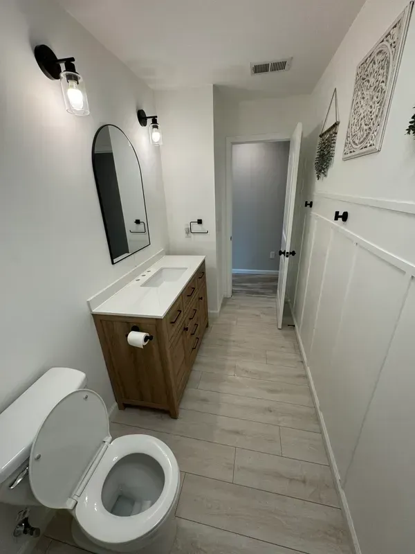 A bathroom with a toilet , sink and mirror.