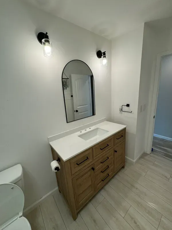 A bathroom with a sink , toilet and mirror.