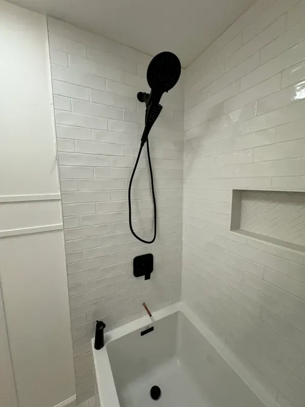 A bathroom with a bathtub and a shower head.
