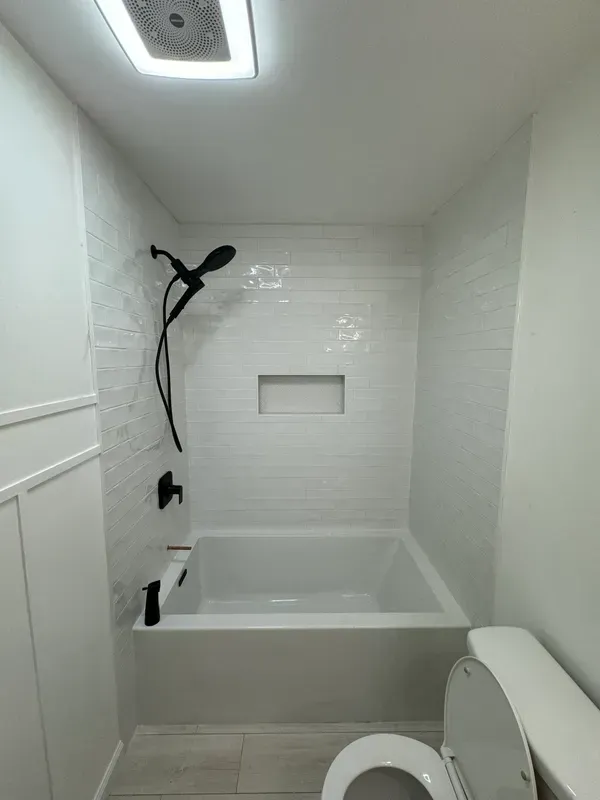 A bathroom with a bathtub , toilet and shower.
