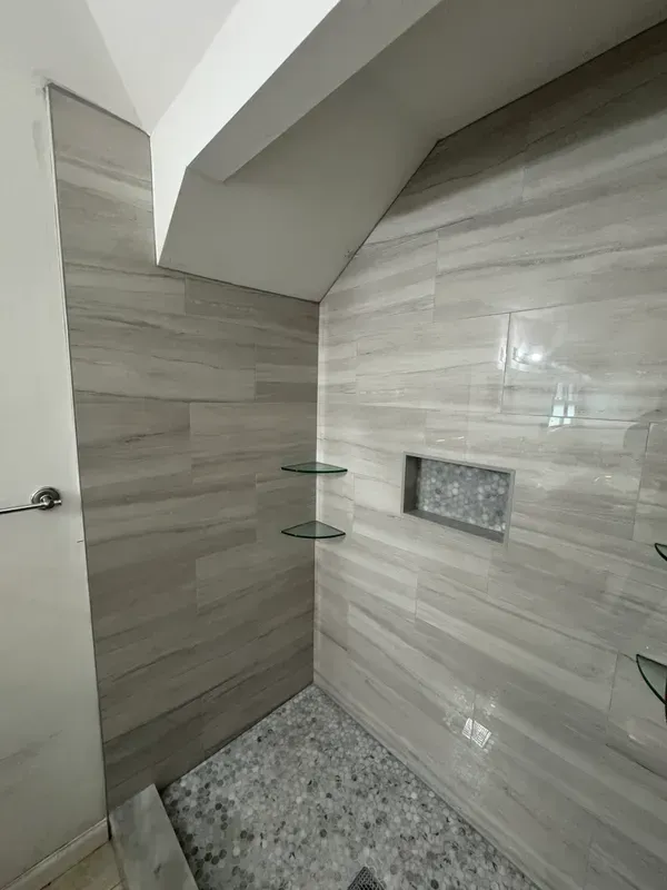 A bathroom with a walk in shower and a tiled wall.