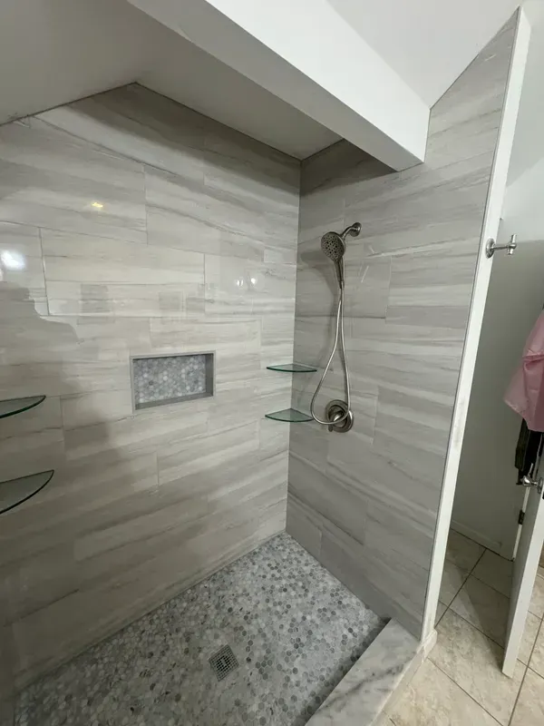 A bathroom with a walk in shower and glass shelves.