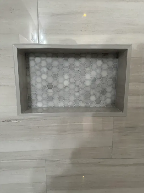 A shower niche in a bathroom with a tiled floor.