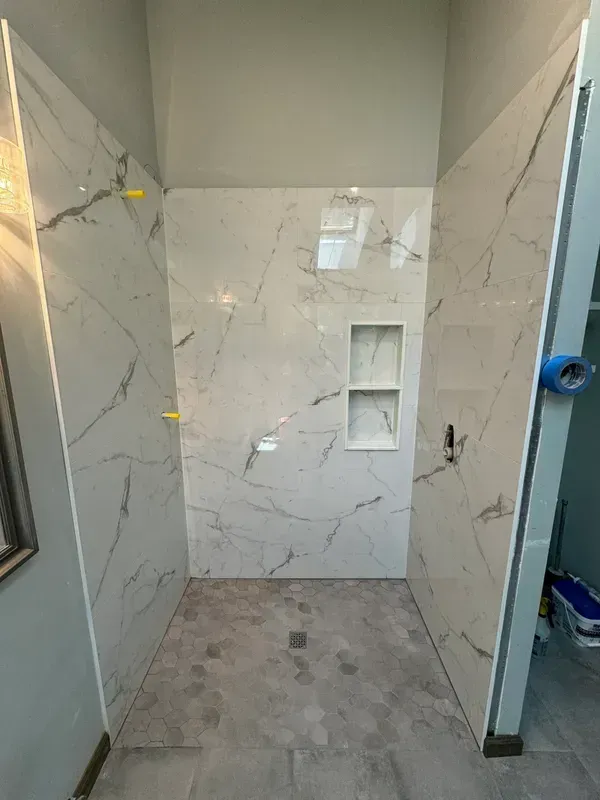 A bathroom with a shower stall and a marble wall.