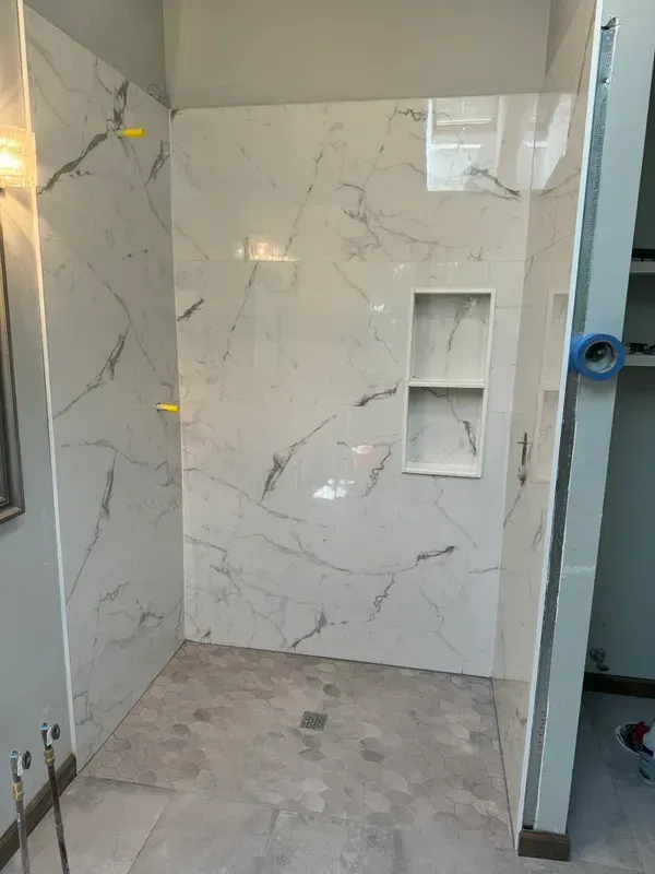 A bathroom with marble tiles and a walk in shower.