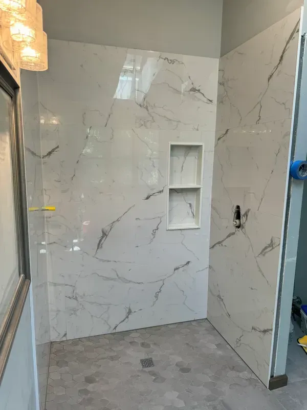 A bathroom with marble tiles and a walk in shower.