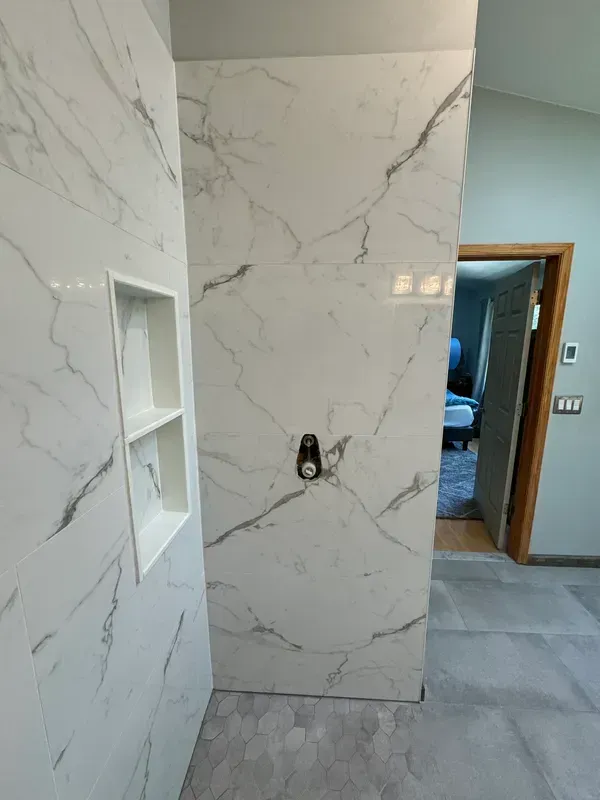 A bathroom with marble tiles and a walk in shower.