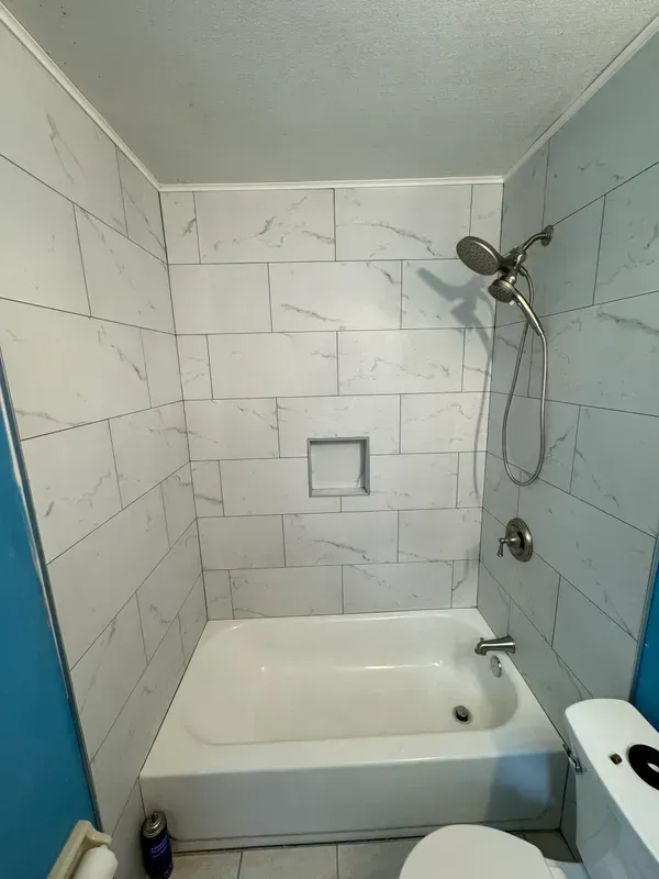 A bathroom with a bathtub , toilet and shower.