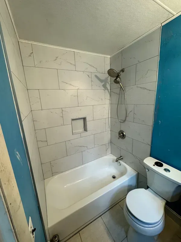 A bathroom with a bathtub , toilet and shower.