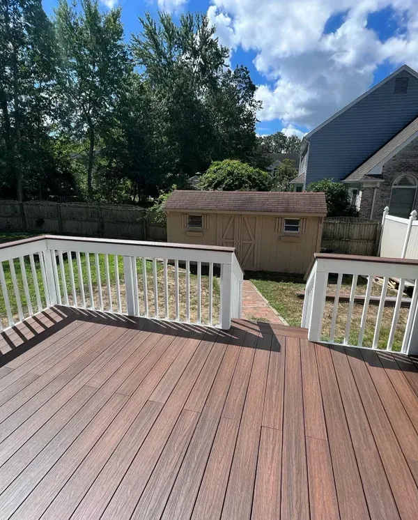 A wooden deck with a white railing and a shed in the background.