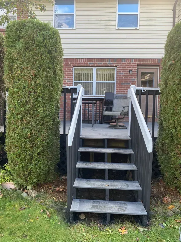 A deck with stairs leading up to it in front of a house.