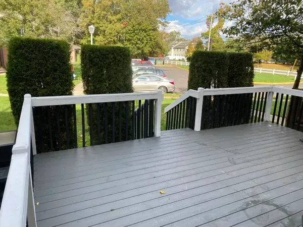 A gray deck with a white railing and stairs leading up to it.